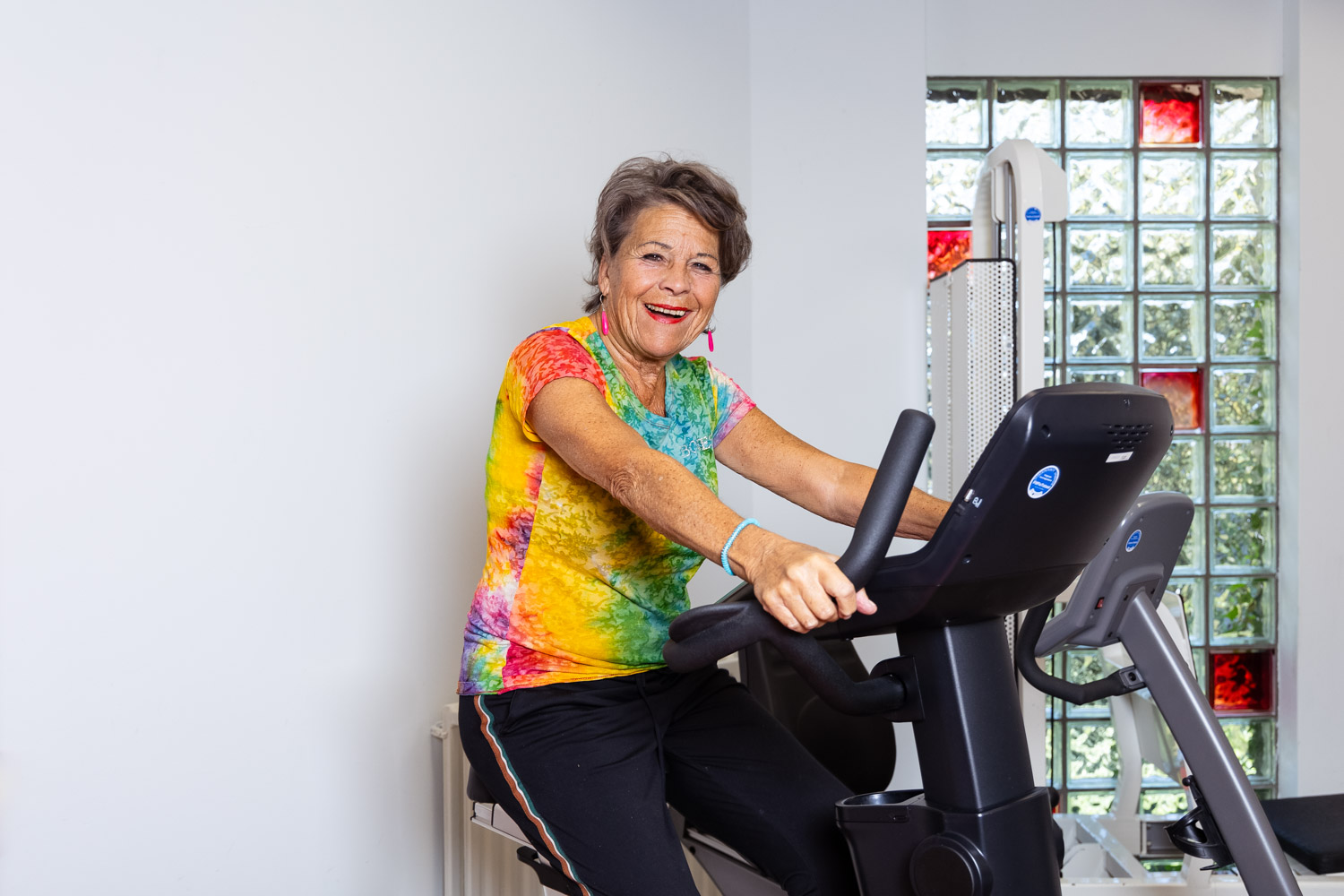 Een vrouw is aan het bewegen op een hometrainer die in een oefenzaal staat.